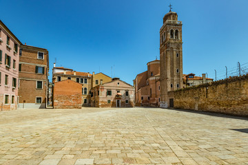 VENICE, ITALY - August 03, 2019: One of the thousands of lovely cozy corners in Venice on a clear sunny day. Locals and tourists strolling along the streets and historical buildings