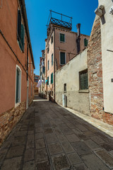 Fototapeta na wymiar VENICE, ITALY - August 03, 2019: One of the thousands of lovely cozy corners in Venice on a clear sunny day. Locals and tourists strolling along the streets and historical buildings