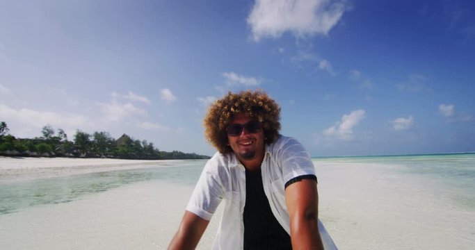 Aerial shot of happy young overweight man is having fun to dancing on a desert beach with clear transparent sea water of a tropical island. Concept of lifestyle, happiness, youth, vacation, holidays 