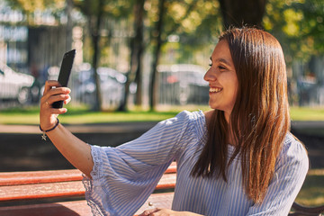 Vertical shot of a girl in a blue shirt taking a selfie