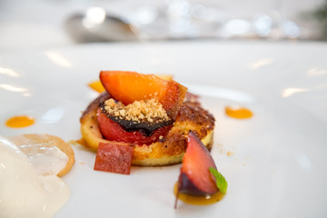 baked peach dessert with berries on a white plate