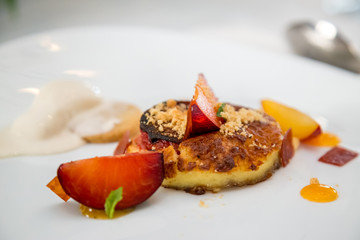 baked peach dessert with berries on a white plate