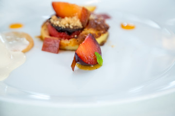 baked peach dessert with berries on a white plate