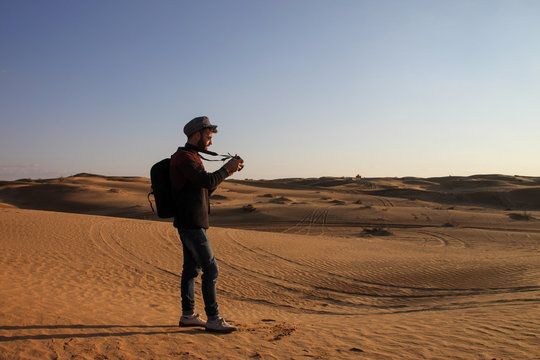 Traveller man with hat and sunglasses taking pictures in the desert