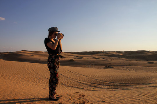 Young woman with hat taking a picture in the desert