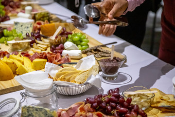 people cutting meat and cheese on wooden board