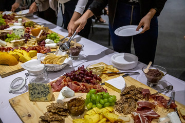 people cutting meat and cheese on wooden board