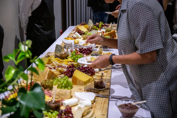 people cutting meat and cheese on wooden board