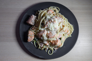Top view of salmon cream pasta on a black plate.