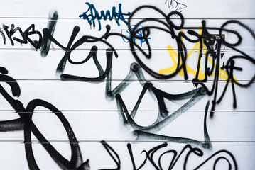 Fototapeta na wymiar Generic black graffiti style spray painted lines on a white wall.