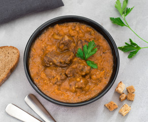 Meat dish goulash of beef, stewed meat with vegetables and tomatoes in a bowl
