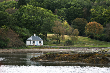 Panoramic view of the rocky shores of Kyles of Bute from the water. Hills and forest in the...