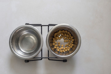 Feeder for animals. Cat's food. Two bowls with cat food and water stand on the floor, top view