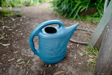 Blue plastic watering can in garden area