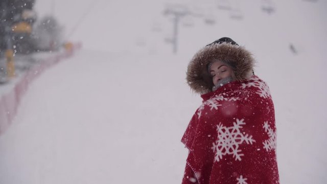 Close up of frozen woman wrapped in a blanket at snowstorm