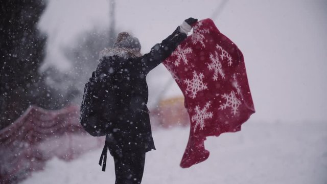 Close up of frozen woman wrapped in a blanket at snowstorm