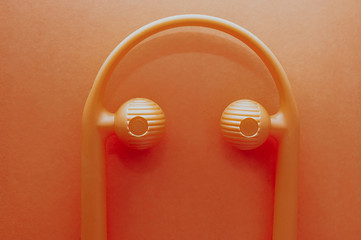 Monochrome orange photo. Orange plastic massager for neck and head in an orange background.
