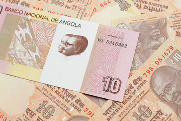 An red and white ten Angolan kwanza bank note on a background of Indian ten rupee bank notes