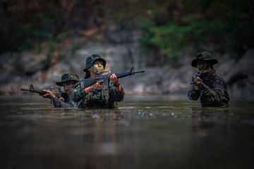 Soldiers with gun are walking along the river. War, soldier army, gun and hostage rescue concept.