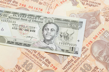 A close up image of a one Ethiopian birr bank note on a background of Indian ten rupee bank notes