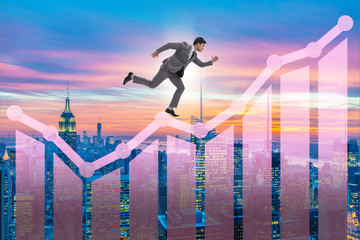 Businessman climbing bar charts in growth concept