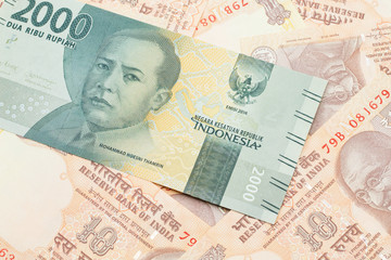 A grey, two thousand Indonesian rupiah bank note with Indian ten rupee bank notes close up in macro