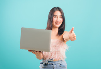 Smiling face portrait asian beautiful woman holding laptop computer and giving thumb up