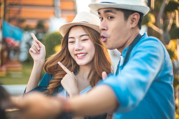 Fototapeta na wymiar Beautiful young dating couple in city making selfie.Happy Asian couple tourist backpackers looking for direction traveling around Thai temple on holidays in Bangkok, Thailand.
