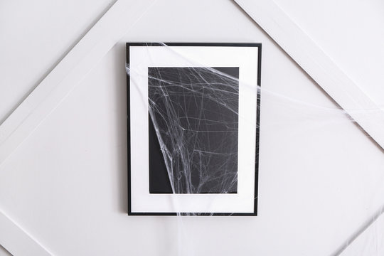 Frame with spider web hanging on wall