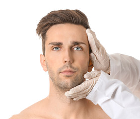 Obraz premium Plastic surgeon touching face of young man on white background
