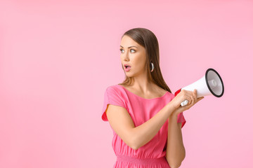 Young woman with megaphone on color background