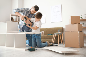 Father and his little son assembling furniture at home