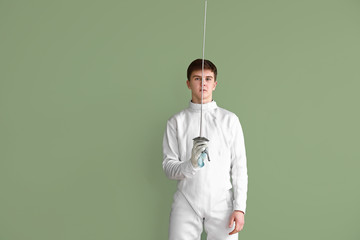 Young male fencer on color background
