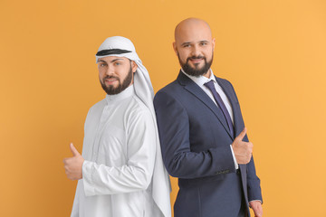 Arab man and his business partner showing thumb-up on color background