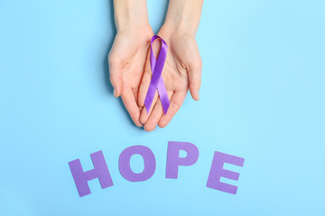 Female hands, word HOPE and violet ribbon on color background. Domestic violence concept