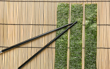 Tasty seaweed sheets and chopsticks on bamboo mat
