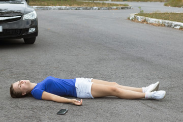 Downed girl by car, young unconscious woman lying on road, asphault with cell mobile smart phone...