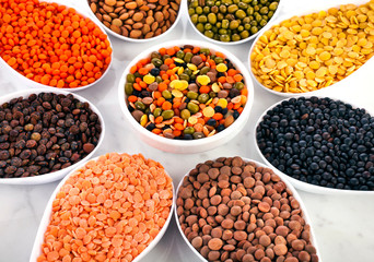 Bowls of various lentils in the shape of flower on a marble background.