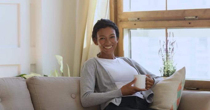 Happy young african american girl holding mug of hot coffee.