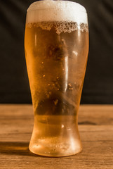 glass of beer with foam on background