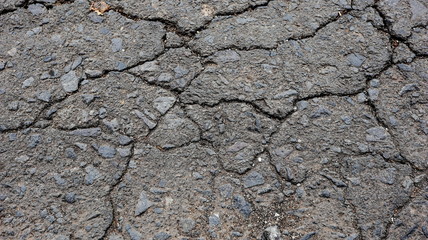 Damaged asphalt road, cracked cracks and scattered stones, with selective focus