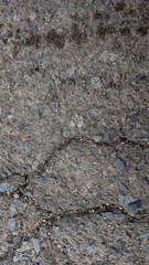Damaged asphalt road, cracked cracks and scattered stones, with selective focus