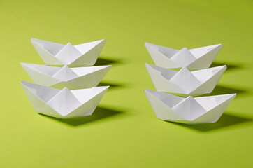 White origami on green background. Group of handmade ship. Concept photo for your project.