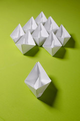 White origami on green background. Group of handmade ship. Concept photo for your project.