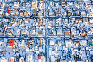 suburb area in sunny winter day. houses roofs covered with snow. aerial view from flying drone