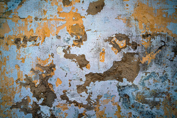 An aged and cracked cement wall with yellow green blue mood and tone
