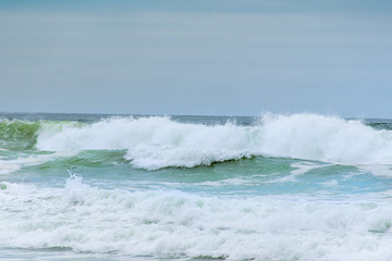 Ocean waves with white foam splashes on a dull cloudy day