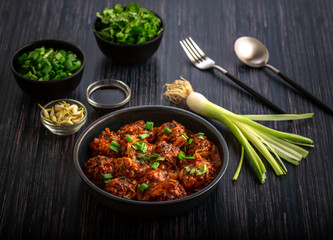 Vegetable manchurian served in a plate with soya sauce and spring onion