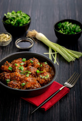 Vegetable manchurian served in a plate with soya sauce and spring onion