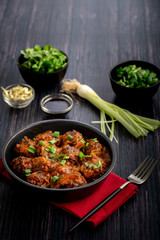 Vegetable manchurian served in a plate with soya sauce and spring onion